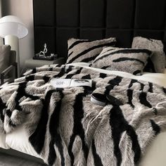 a bed with black and white fur on the comforter, pillows and pillow cases