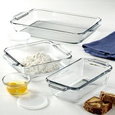 glass baking dishes with bread, butter and other ingredients on a white tableclothed surface