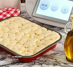 a baking pan filled with food next to a bottle of oil