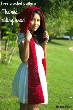 a woman wearing a red knitted hood and white dress is standing in the grass