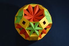 an origami ball on a black background with red, yellow and green colors