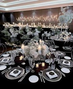 a table set with white flowers, candles and place settings for an elegant dinner party