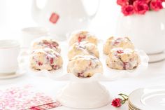 a white plate topped with cookies covered in icing next to cups and saucers