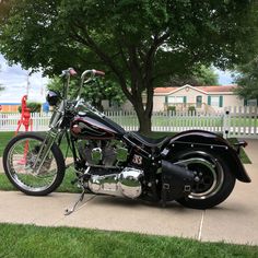 a black motorcycle parked on the sidewalk next to a tree