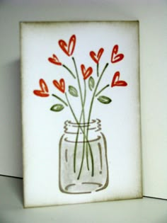 a glass vase with red flowers in it on a white shelf next to a wall