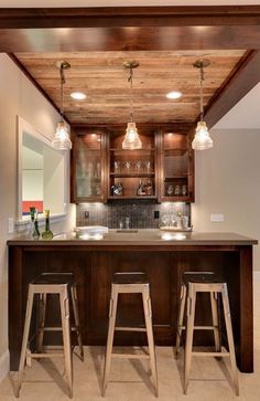 a kitchen with two bar stools in front of the counter and lights above it