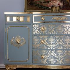 a blue and gold painted dresser with ornate designs