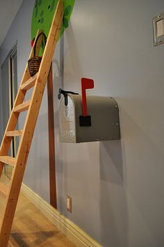 a wooden ladder leaning up against a wall with mailboxes on it and a green frog