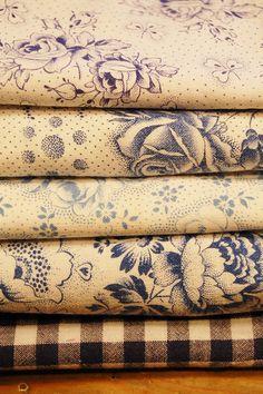 four different fabrics are stacked on top of each other, one is blue and the other has white flowers