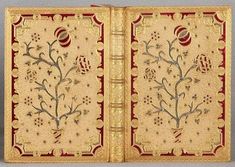 an open book with gold and red designs on the front cover, sitting on a gray surface