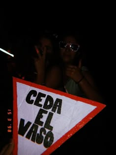 two people holding up a sign that says ceda el vaso in spanish and english