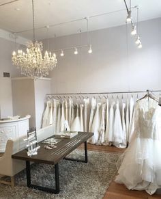 a room filled with lots of white wedding gowns