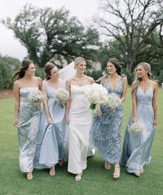 bridesmaids in blue dresses and bouquets walking on the grass