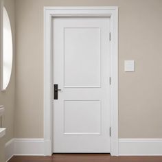 an empty room with a white door and brown floor