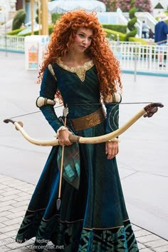 a woman dressed as merida from brave, holding an arrow and bow in her hands