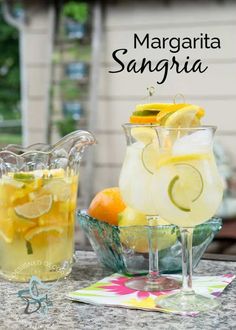 two pitchers filled with lemon and limeade sitting on top of a table next to a pitcher