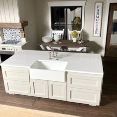 a model kitchen with white cabinets and counter tops, including a sink in the center