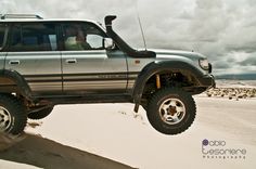 a silver four door suv driving through the desert