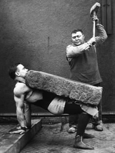 two men are doing exercises in front of a wall with a large object on it