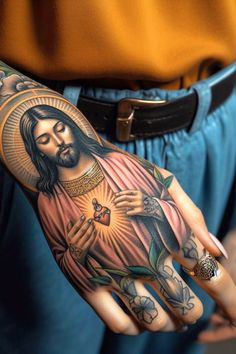 a person with tattoos on their arms and hand holding a cross in front of them