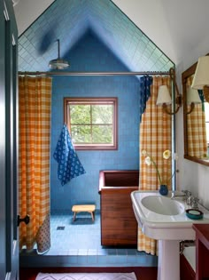 a bathroom with blue tile and orange curtains