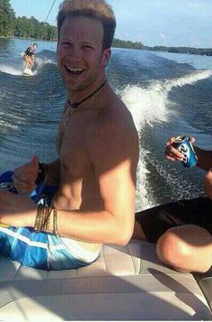 two men riding on the back of a boat with water skis in the background