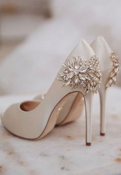 a pair of white high heel shoes on top of a marble table