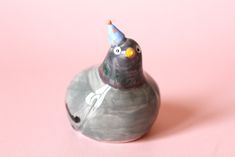 a ceramic bird with a party hat on it's head sitting on a pink surface