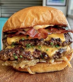 a cheeseburger with bacon and onions on a wooden table