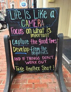 a sign that is sitting on the side of a building saying life is like a camera focus on what is capture the good times