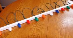 a wooden table topped with a name sign and string lights on the end of it