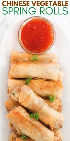 chinese vegetable spring rolls on a white plate with dipping sauce in the middle and text overlay