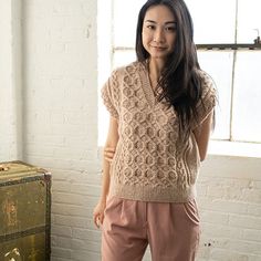 a woman standing in front of a window wearing a sweater