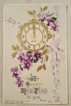 a happy new year greeting card with purple flowers and a clock on the front side