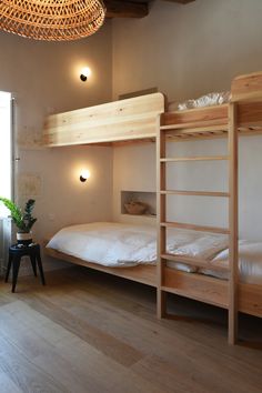 bunk beds in a room with wooden flooring and lights on the wall above them