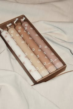 four candles in a box on a bed