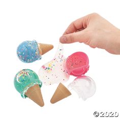 three ice cream cones with sprinkles are being held by a hand