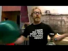 a man with glasses holding a green ball in front of him and another person wearing a black t - shirt that says, i have no idea what you are talking about