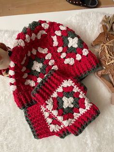 two red and white crocheted afghans sitting on top of a rug next to shoes