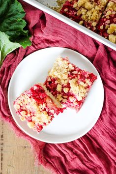 two pieces of cake on a plate next to a pan of crumbled toppings