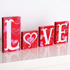 the word love spelled with hearts in red and white painted wood blocks on a shelf