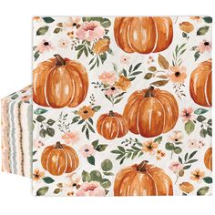 two napkins with orange pumpkins and flowers on them, one is folded to the side