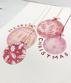 a christmas card with three ornaments hanging from it's strings and the words merry christmas