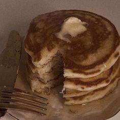 a stack of pancakes sitting on top of a plate next to a knife and fork