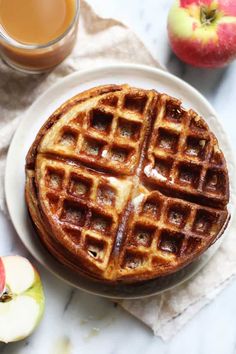 a waffle on a plate next to an apple