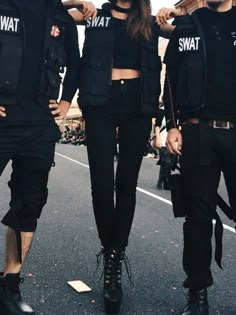 three people in black outfits standing on the street