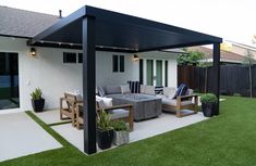 an outdoor living area with couches, tables and potted plants on the grass