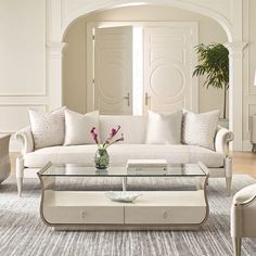 a living room filled with furniture and a glass top coffee table in front of a doorway