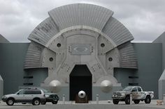 two trucks are parked in front of a building with large round windows and circular doorways