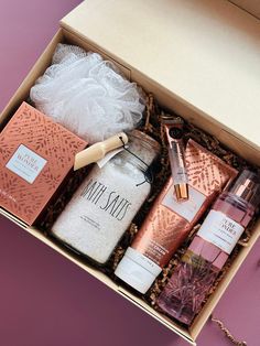 an open gift box containing body care products on a pink surface with lace and beads